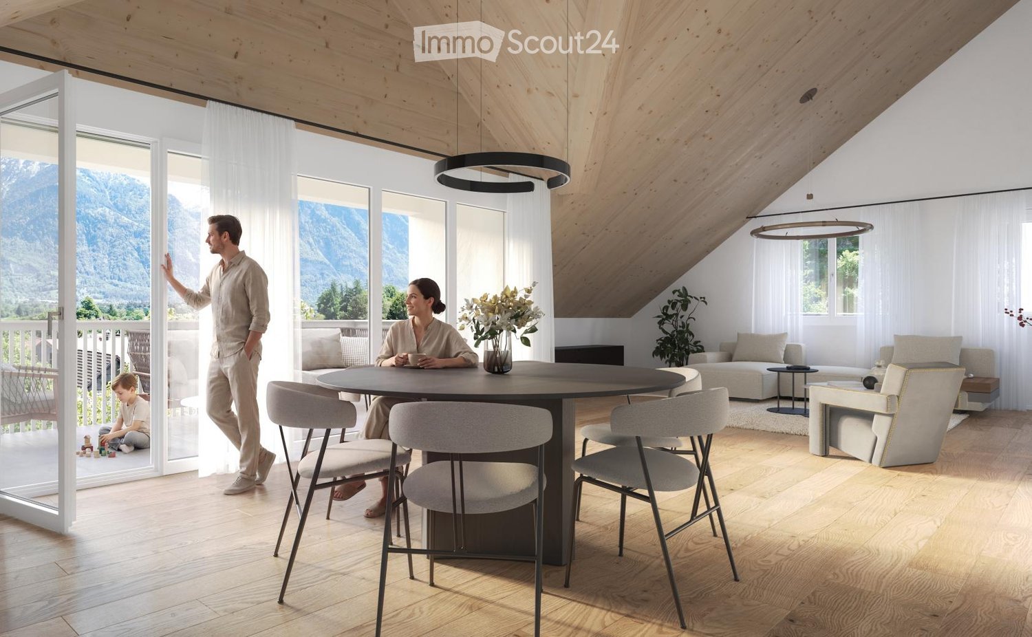 Bright, modern living and dining area with wooden floors, large windows, and a view of mountains. Features a round dining table with chairs, a sofa, coffee table, and decorative vase with flowers.