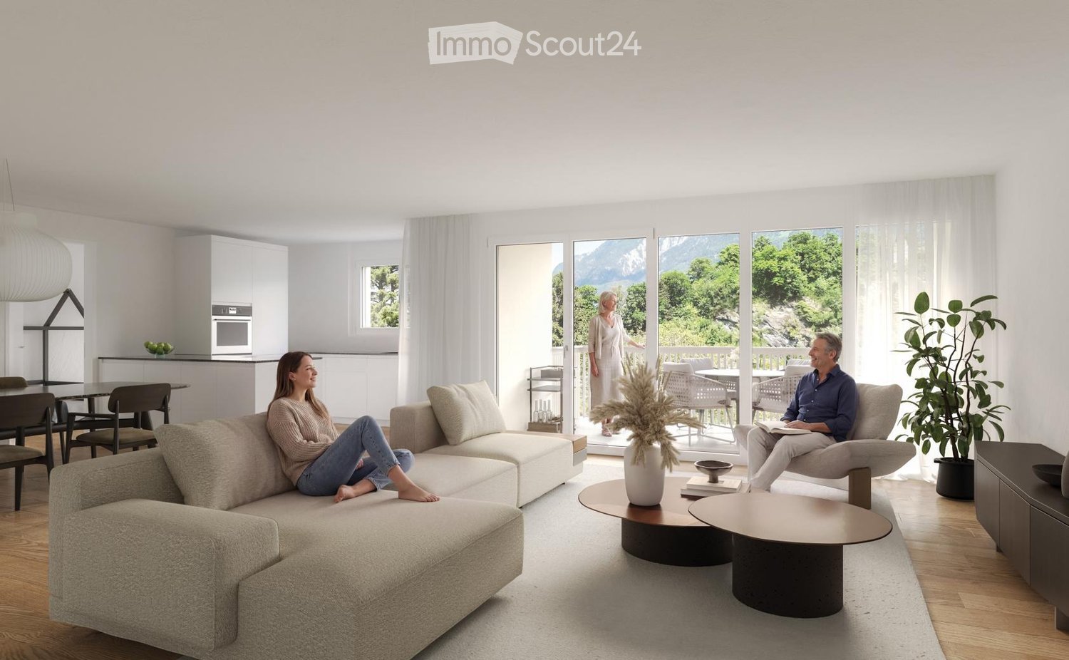 Bright living room with large windows offering a scenic mountain view. Features a beige sectional sofa, two coffee tables, a chair, a dining area with a table and chairs, and a kitchen area with cabinets and appliances.