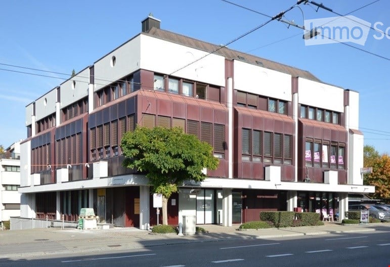 3 story building, red and white exterior, multiple windows, tree in front, cars parked on the side