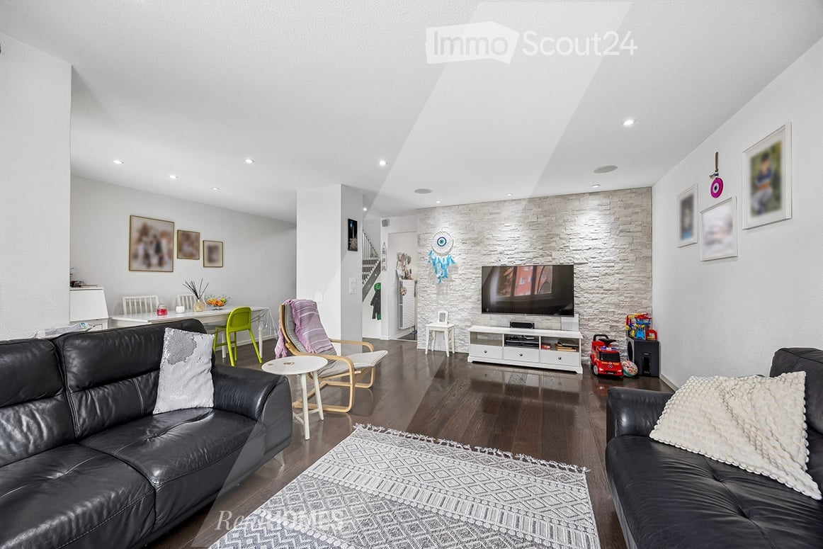 modern living room, black leather sofas, white rug, white entertainment center, flat screen TV, white walls, wooden floor