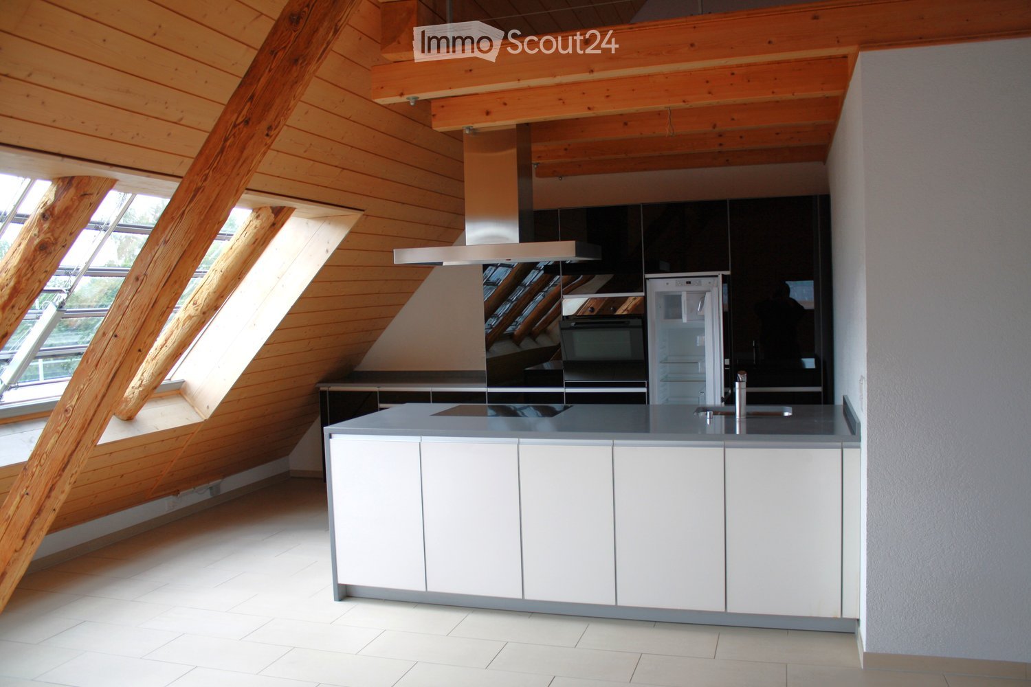 Modern kitchen with white cabinets, a central island, stainless steel appliances, and large skylight windows.