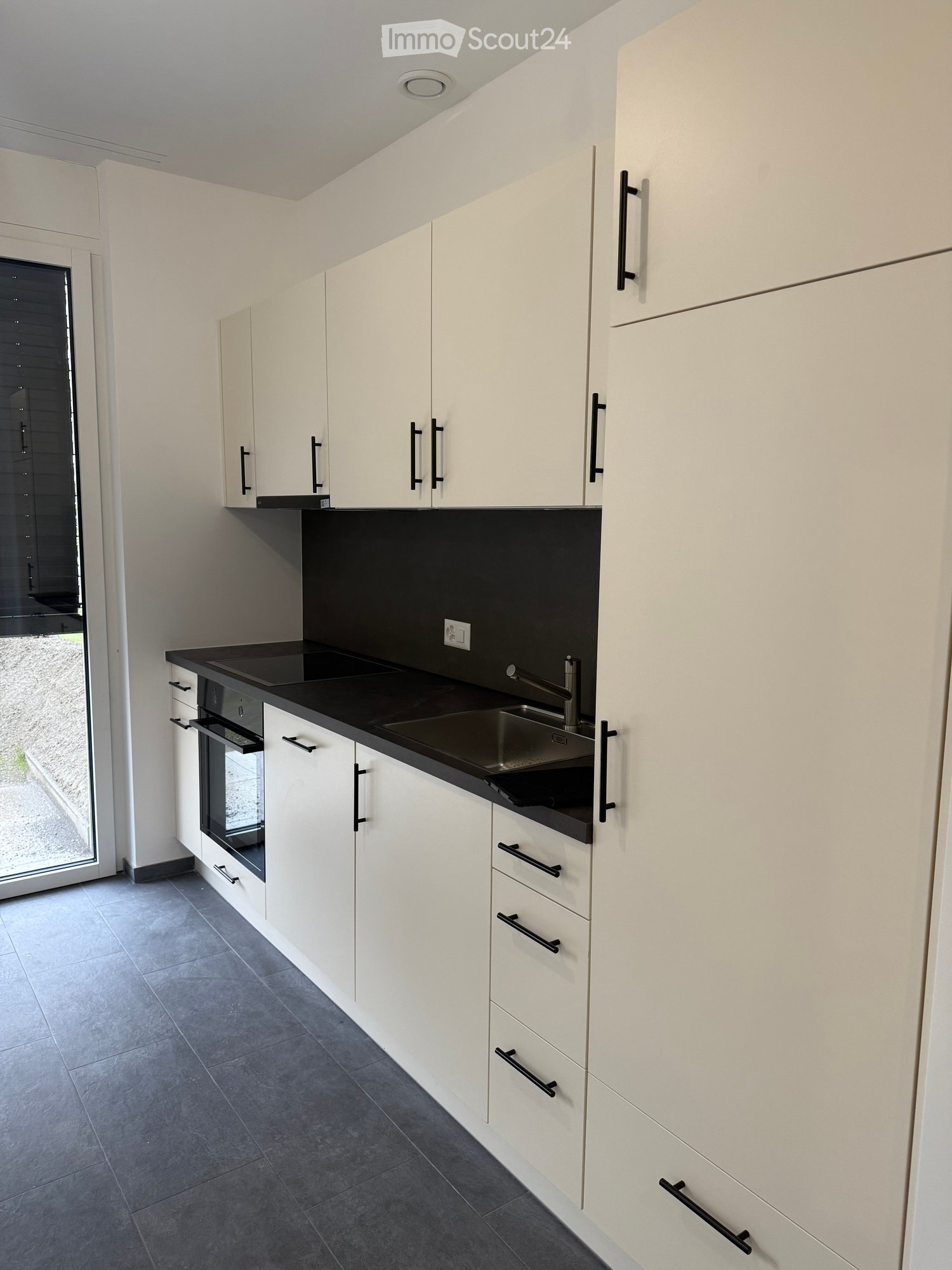Modern kitchen with white cabinets, black countertops, and stainless steel sink and faucet.