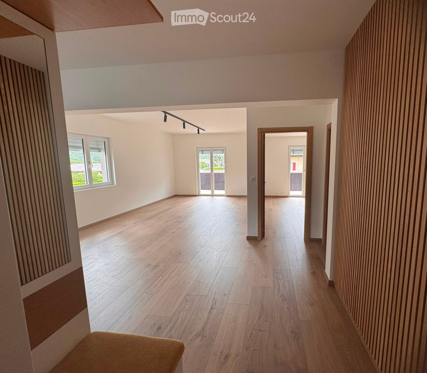 Empty room with wooden flooring, white walls, and large windows. No furniture or equipment present.