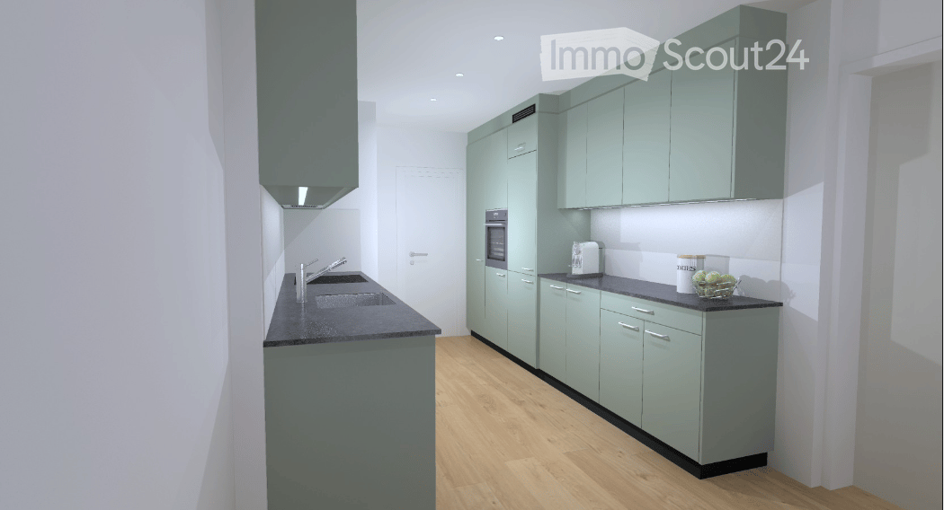 Modern kitchen with light green cabinets, black countertop, wooden flooring, and stainless steel sink and faucet.