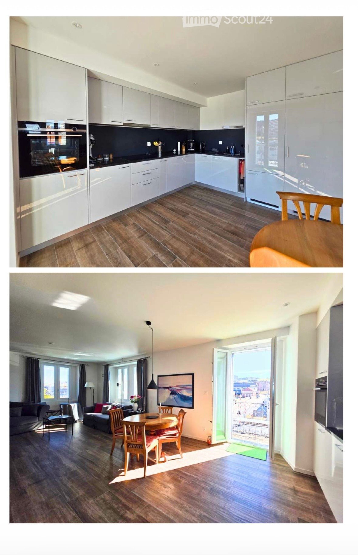 Modern kitchen with white cabinets, black countertops, and stainless steel appliances. Adjacent living area features a sofa, dining table, chairs, and a large window with a view.