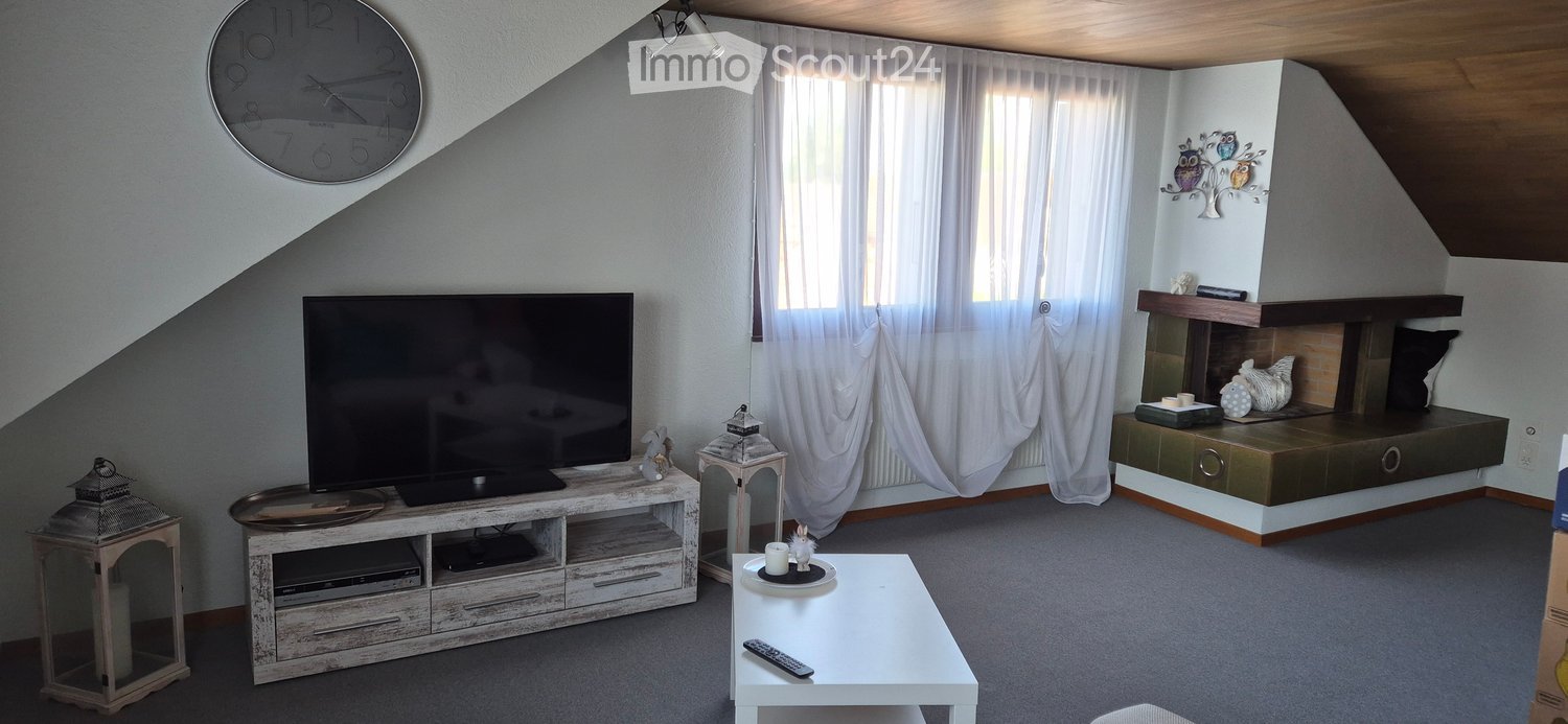 Modern living room with a large television on a wooden stand, a white coffee table, and decorative items including a lantern and a clock on the wall.