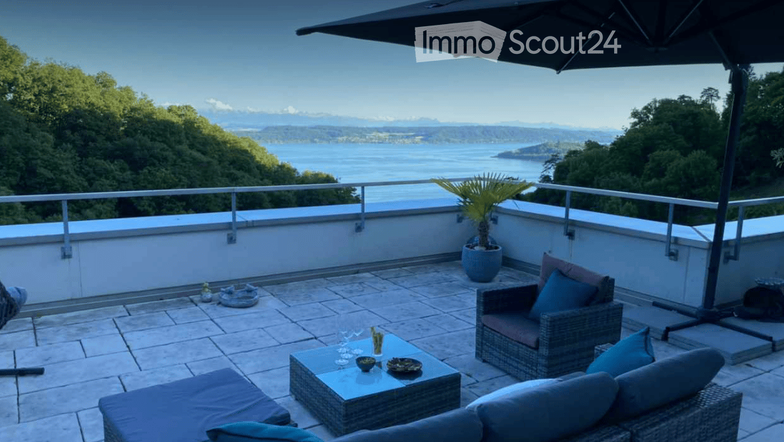 Outdoor seating area with a table, chairs, and a couch, a potted plant, a view of the sea and mountains
