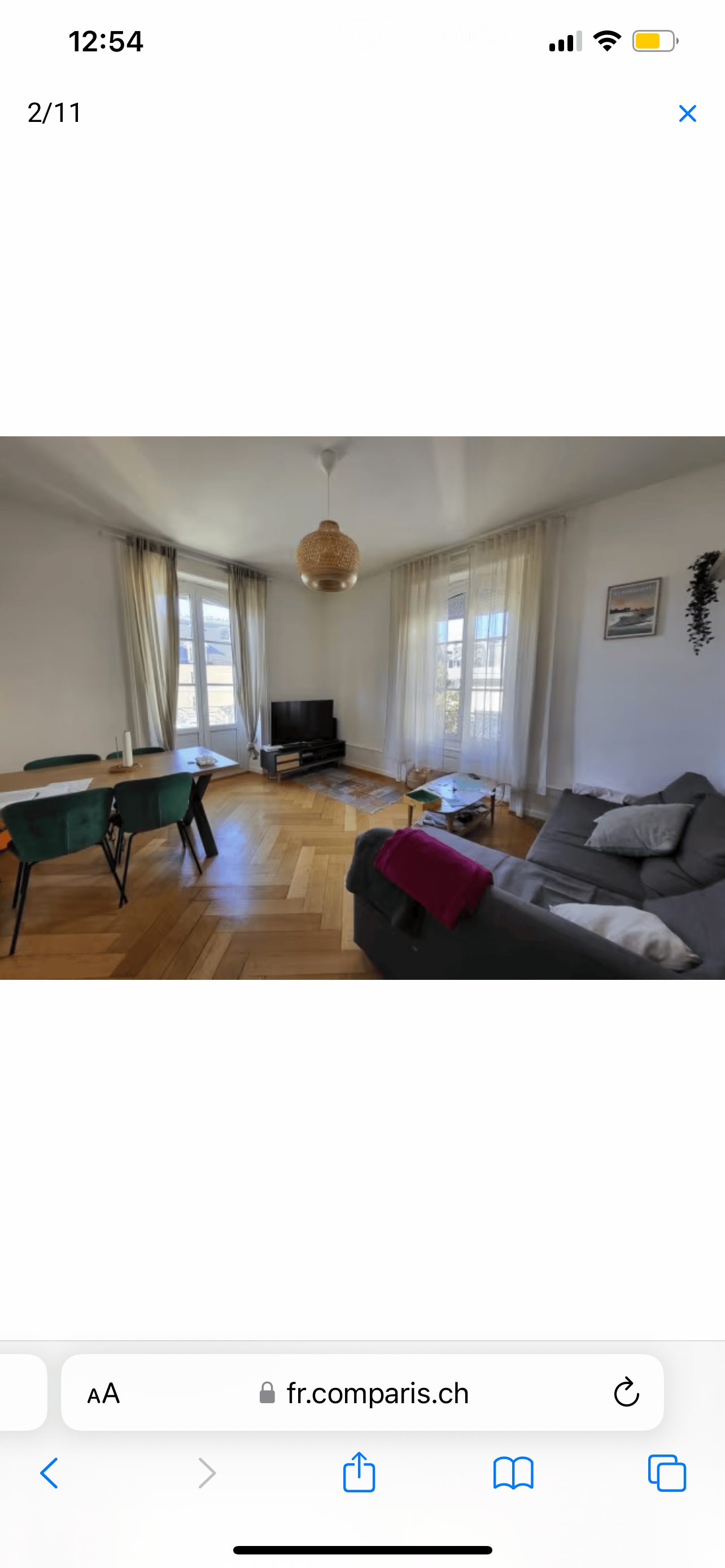 A modern living room with a grey sectional sofa, coffee table, dining table with chairs, television, pendant light, and picture frame on the wall.
