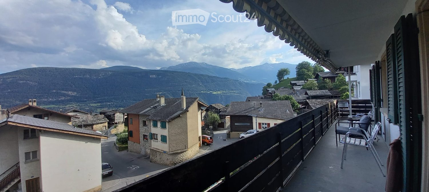 Balcony with a scenic mountain view, featuring a table and chairs.