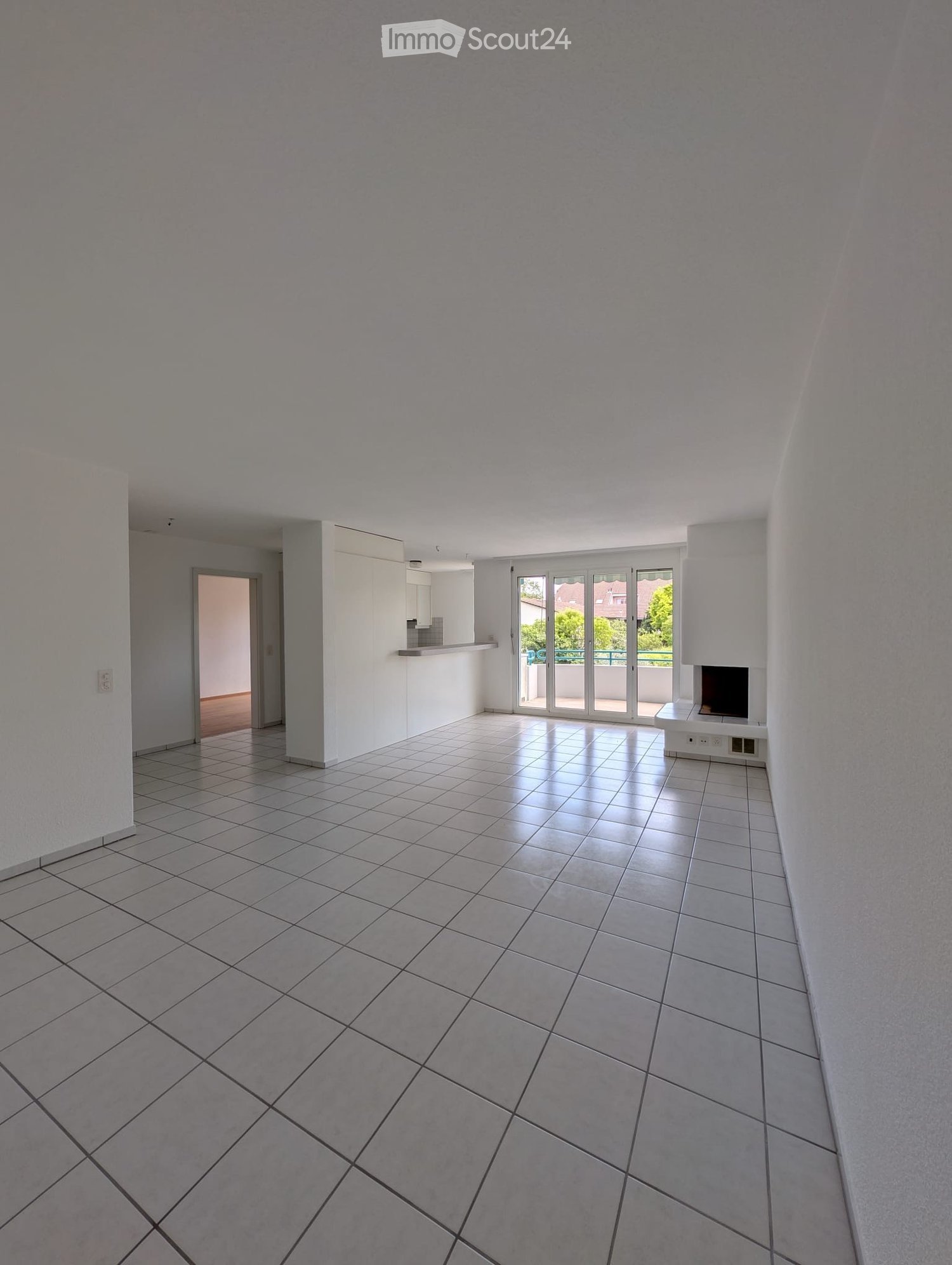 Empty room with tiled floor, white walls, and large sliding glass doors leading to a balcony.