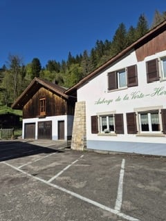 Two-story building with a wooden roof and white facade, featuring a parking lot in front.