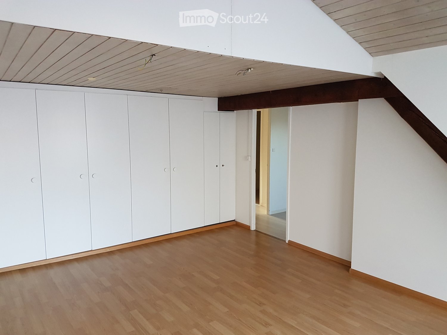wooden floors, white walls, multiple cabinets, door to another room