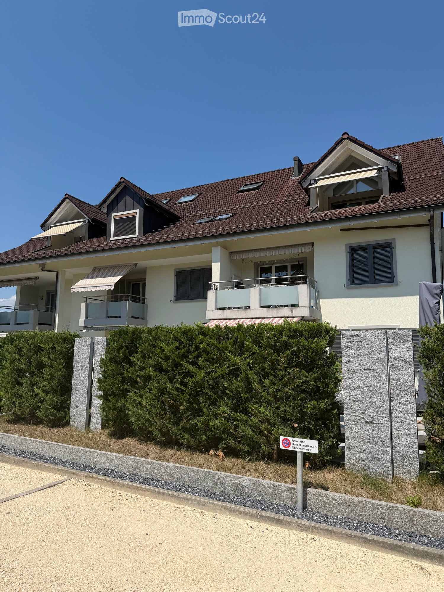 Two-story house with a red-tiled roof, white walls, multiple windows, and balconies.