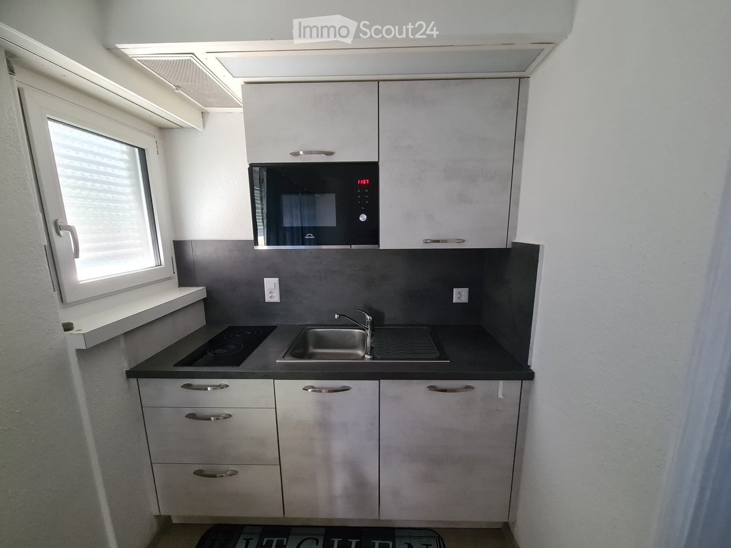 Modern kitchen with white cabinets, black countertop, microwave, electric stove, and sink.