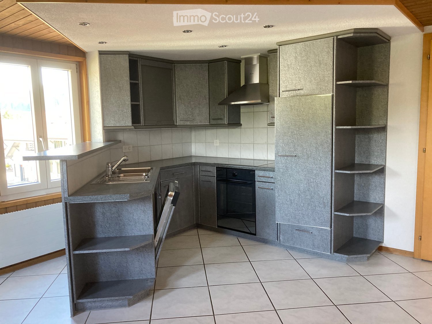 Modern kitchen with grey cabinets, a central island, and built-in appliances including a dishwasher and sink.