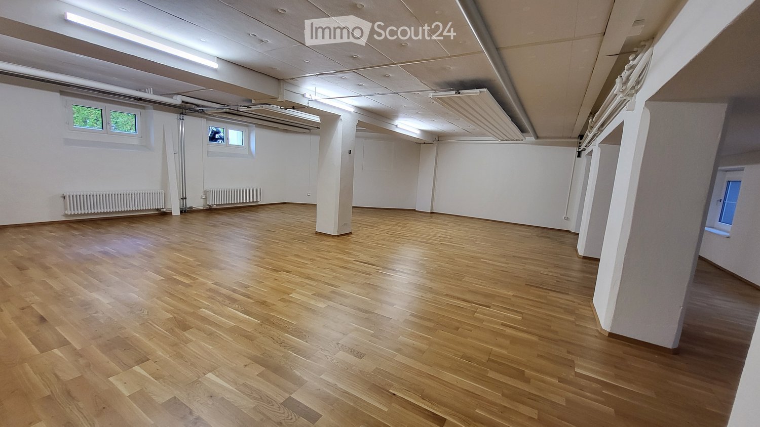 Empty room with wooden flooring, white walls, and exposed ceiling beams. No furniture or equipment present.