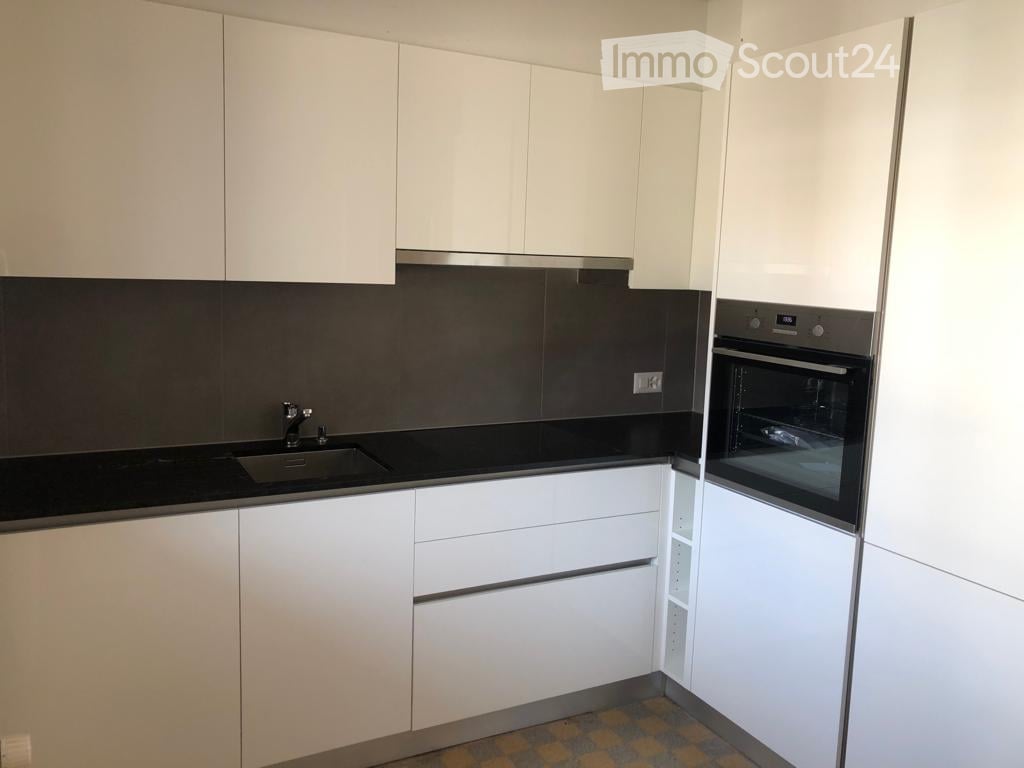 Modern kitchen with white cabinets, black countertops, and stainless steel appliances including a sink and oven.