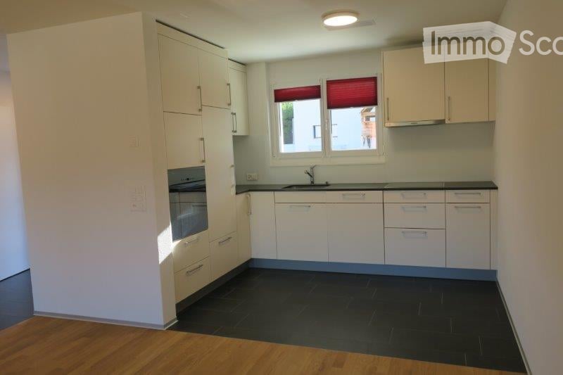 Modern kitchen with white cabinets, black countertops, and a dark tiled floor. Features a sink with a faucet and an oven built into the cabinetry.