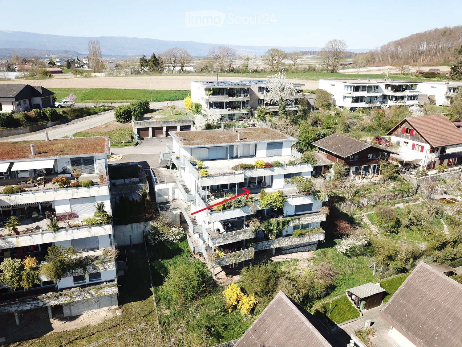 Aerial view of a residential area with multiple modern houses, balconies, and surrounding greenery.