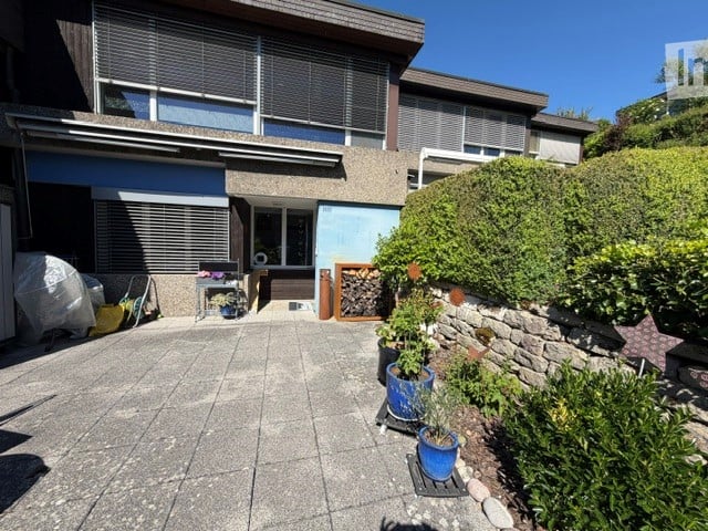 Courtyard area with paved tiles, small table with potted plants, and a stack of firewood near a stone wall.