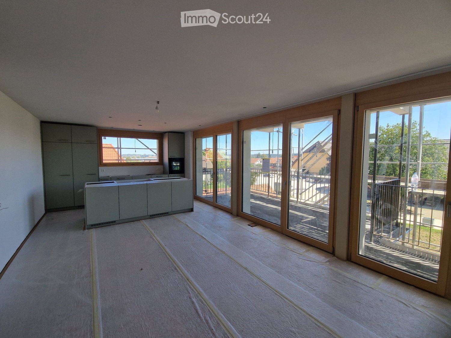 Empty room with light wooden flooring, grey cabinets, and large glass sliding doors leading to a balcony.