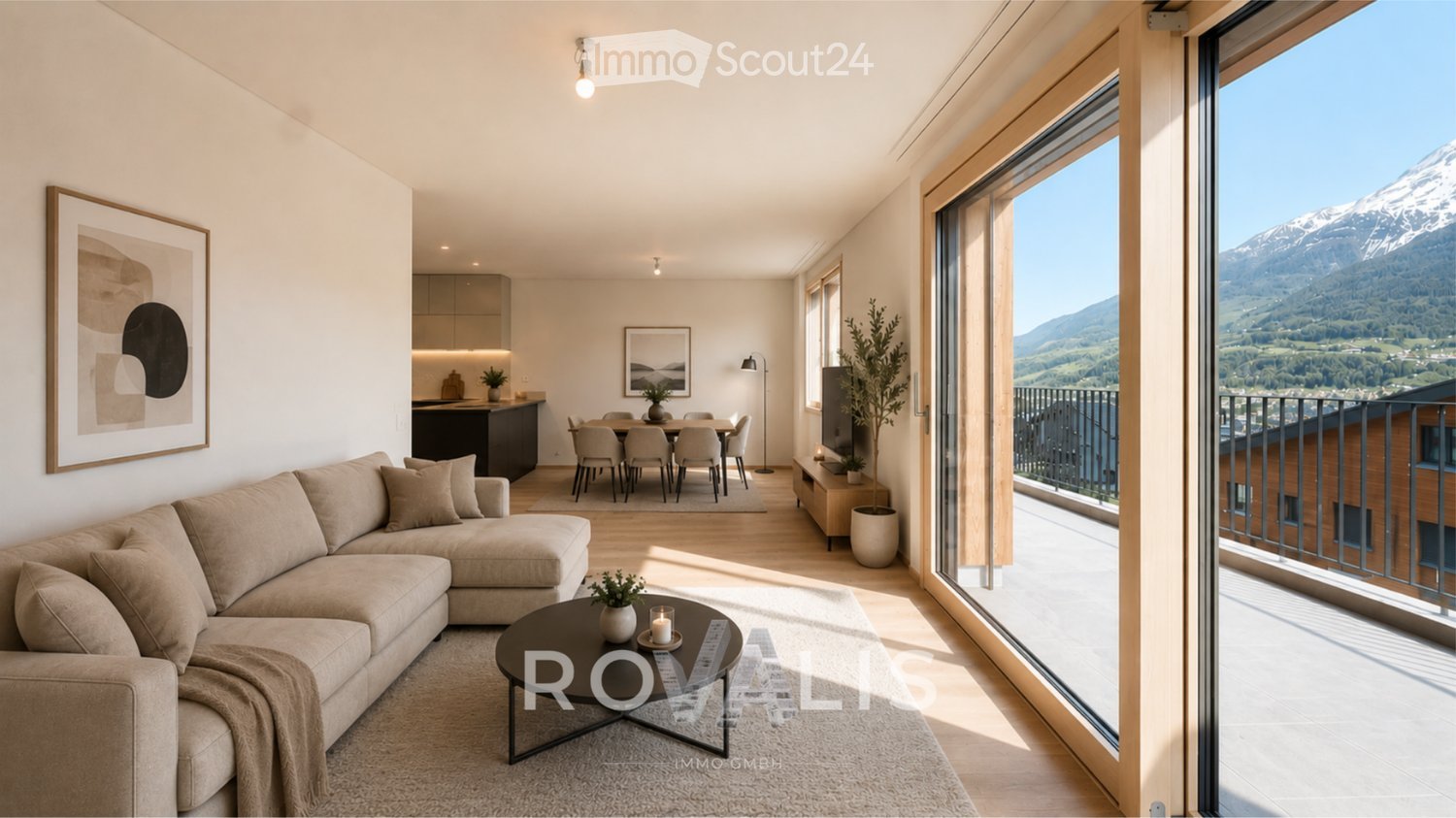 Modern, open-plan living and dining area with large windows offering a scenic mountain view. Features a sectional sofa, coffee table, dining table with chairs, kitchen island, and decorative elements.