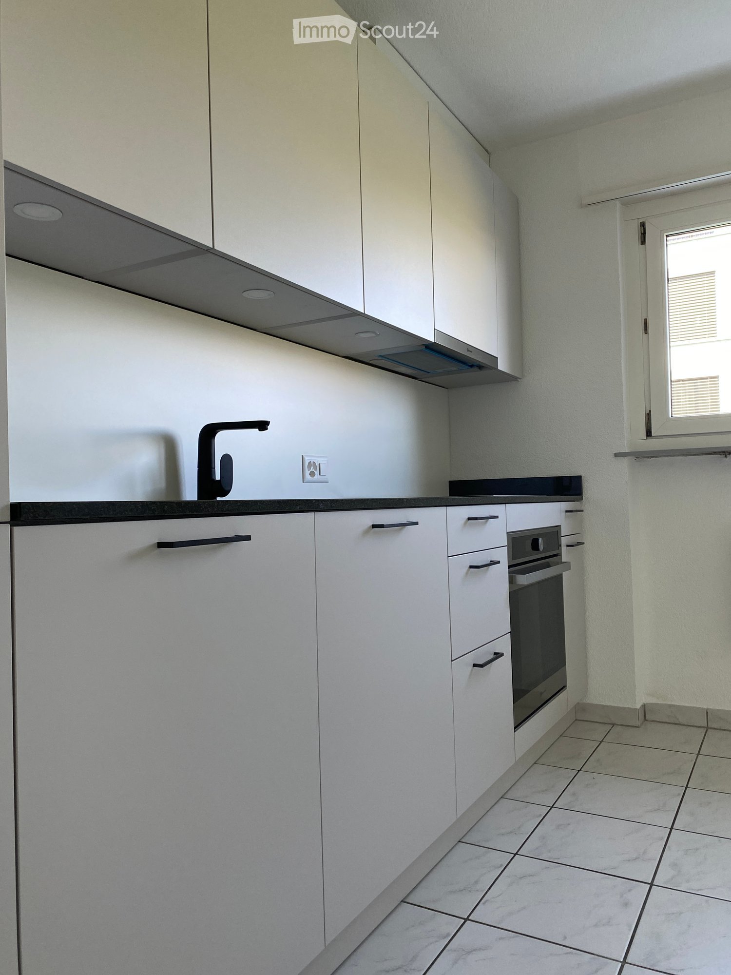 modern minimalist kitchen, white cabinets, black countertop, faucet, built-in oven, dishwasher