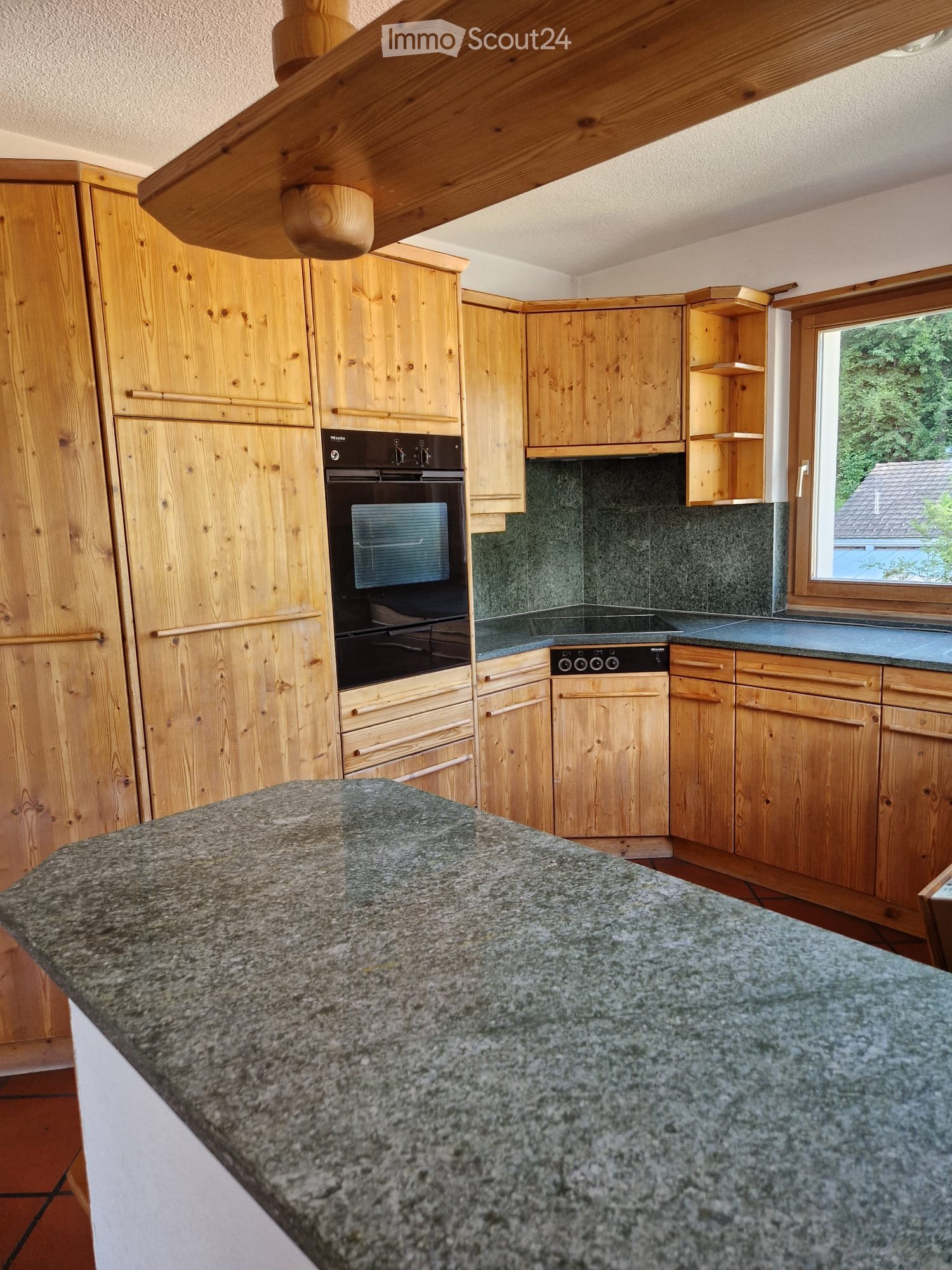 Wooden kitchen with granite countertop, built-in oven, and wooden cabinets.