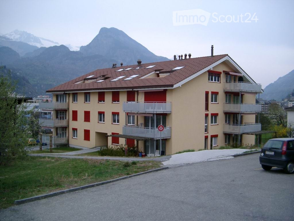 3 story apartment building, beige exterior, red trim, multiple balconies, mountain view