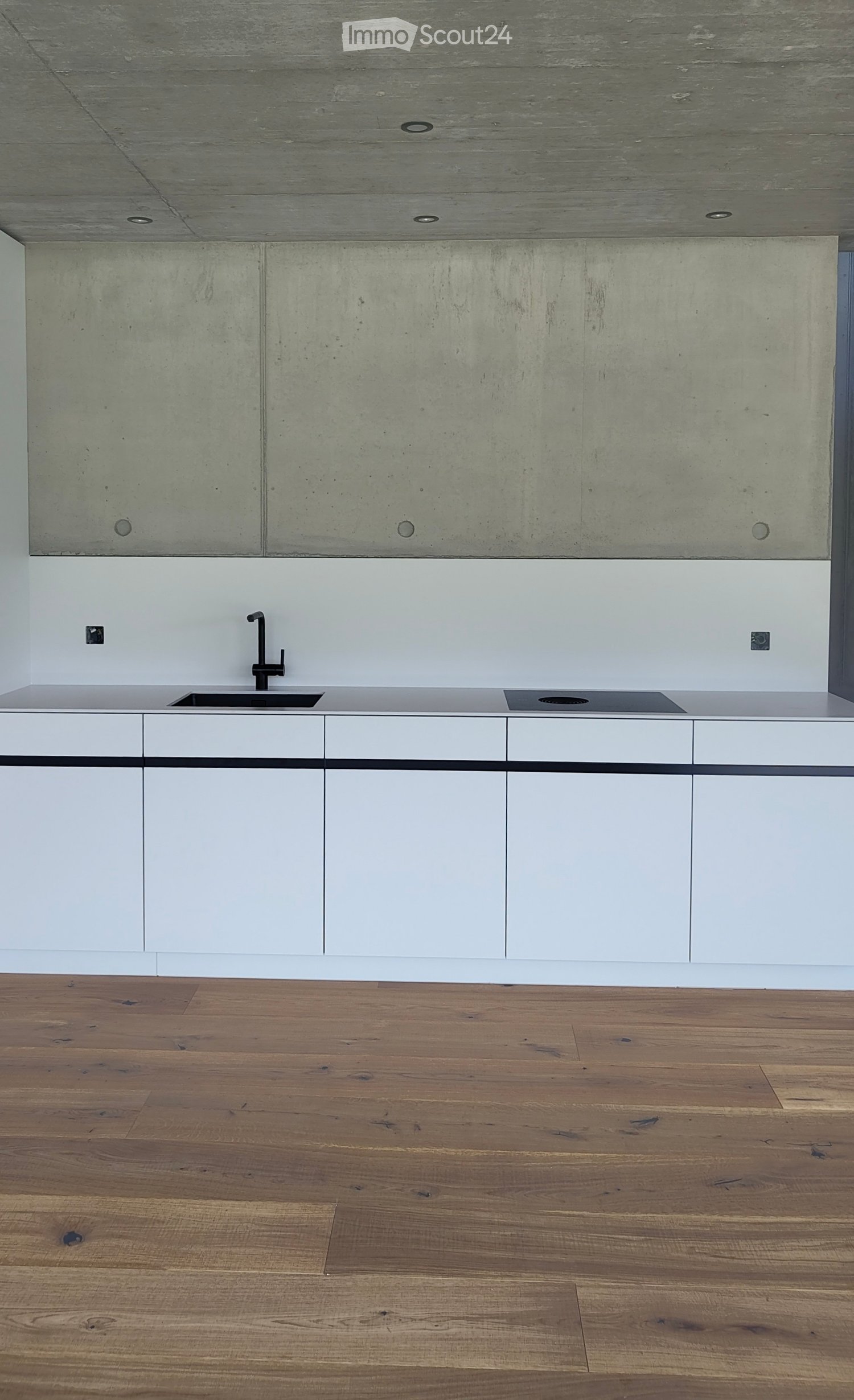 Modern kitchen with white cabinets, a sleek sink, and a wooden floor.