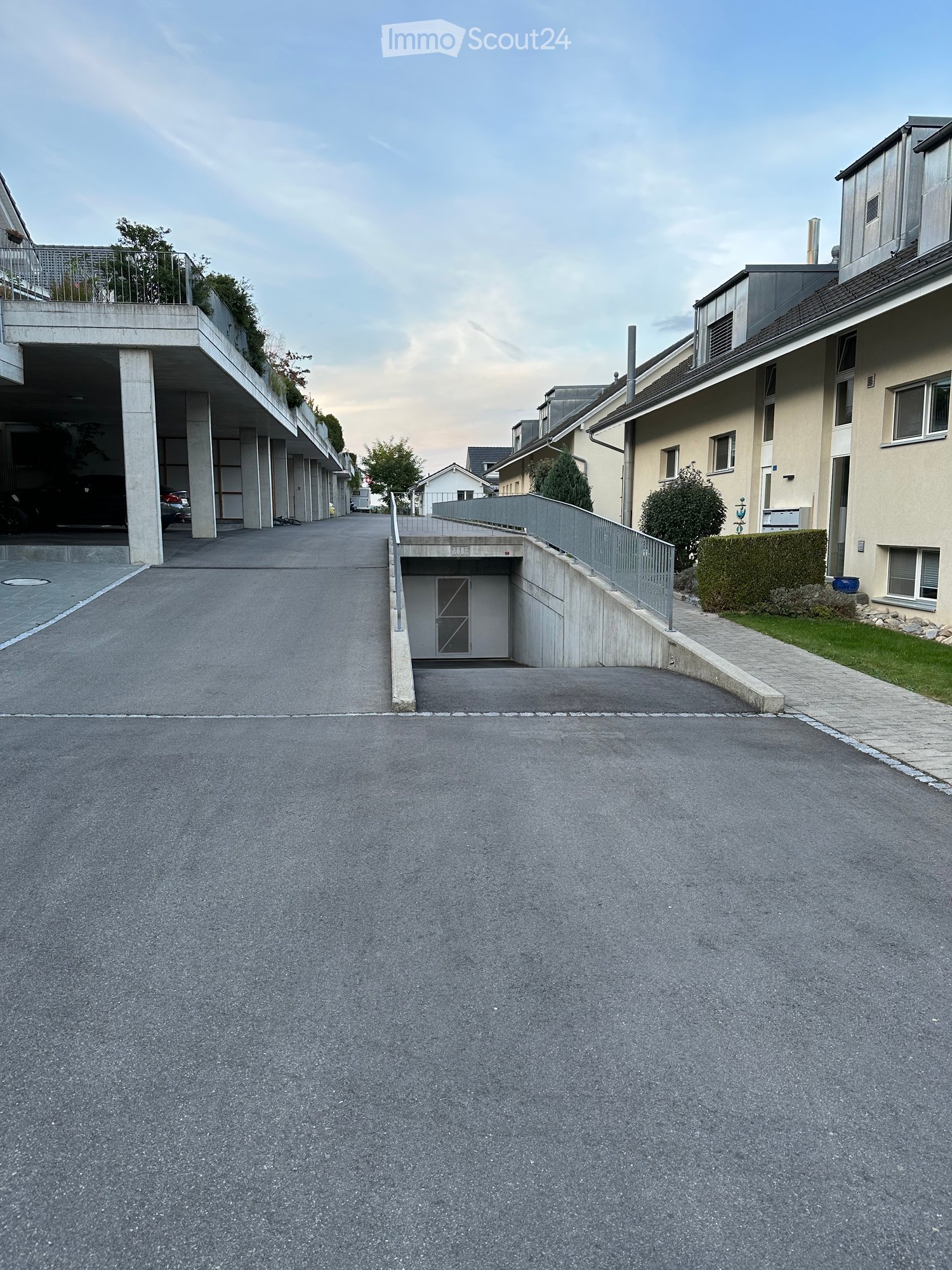 Apartment car park, covered garages, one parked car, large concrete area