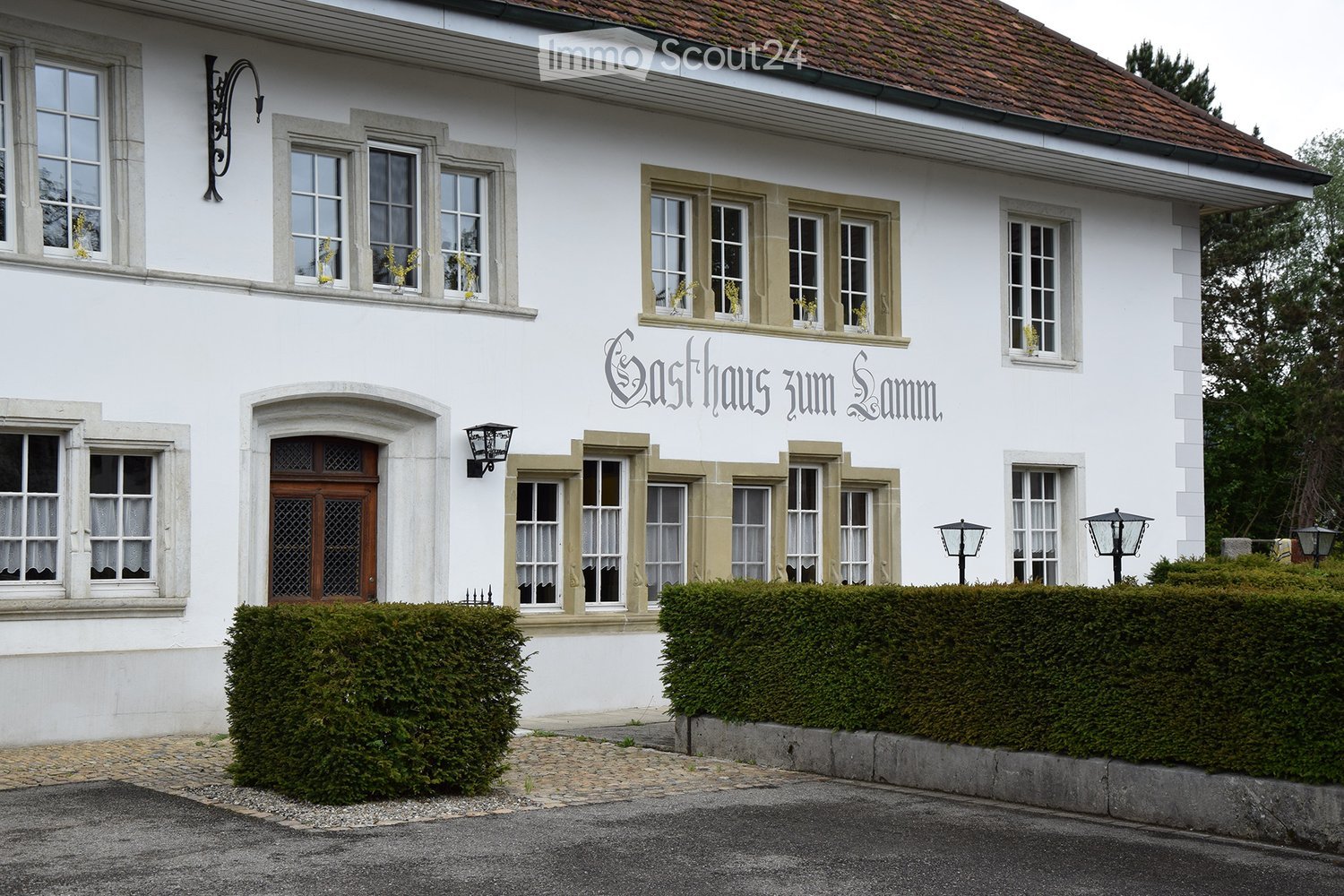 White building with multiple windows, decorative stone trim, and a sign reading "Gasthaus zum Lamm".