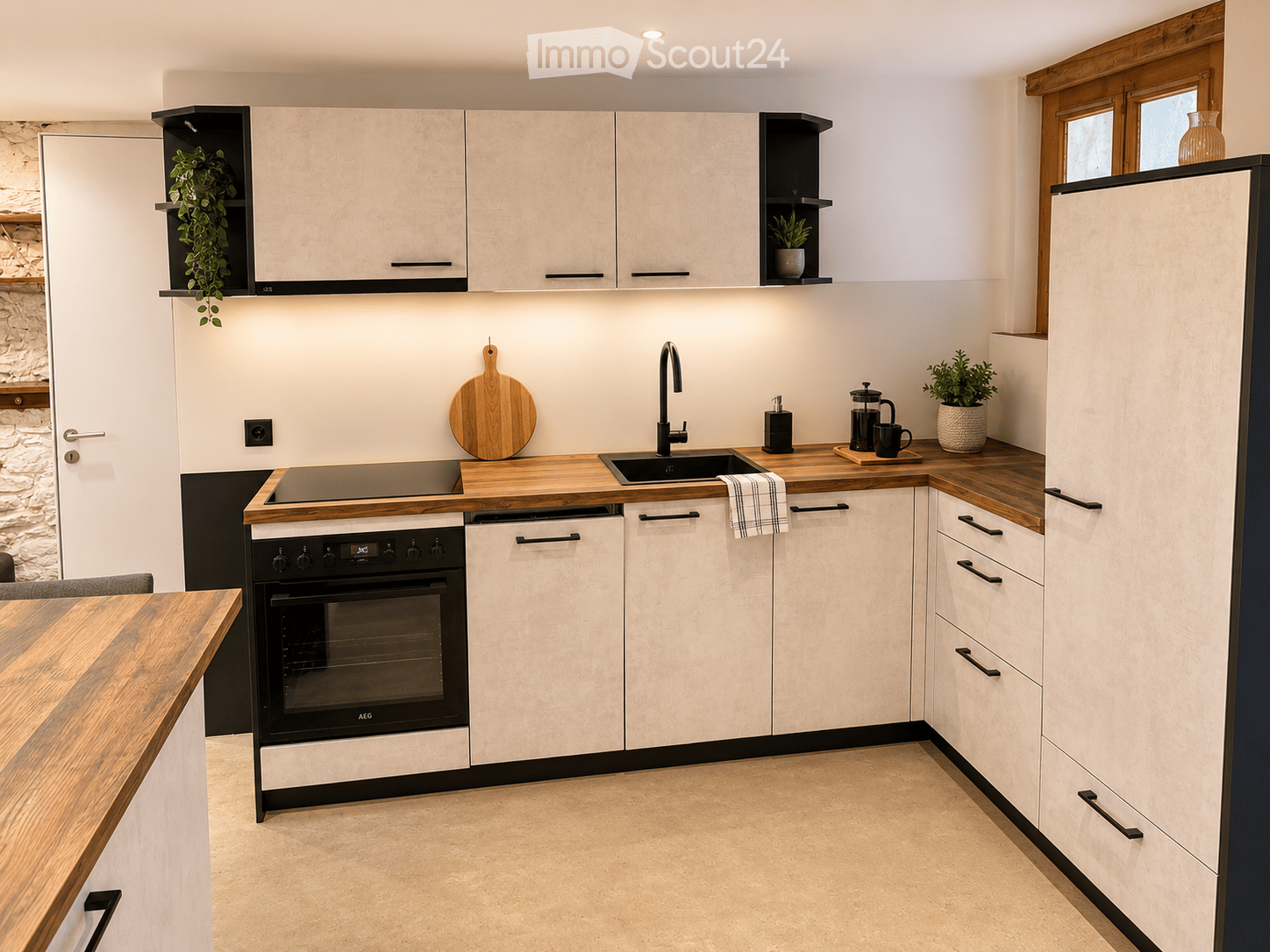 Modern kitchen with white cabinets, wooden countertops, built-in oven, dishwasher, sink, and various appliances.