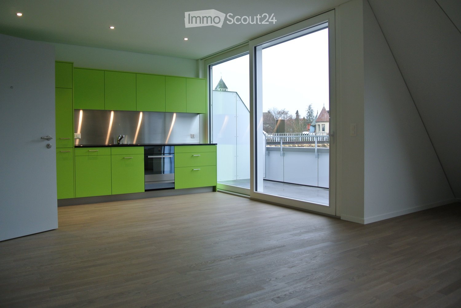 Lime green cupboards, glass door to the balcony, stainless steel oven, wooden floor