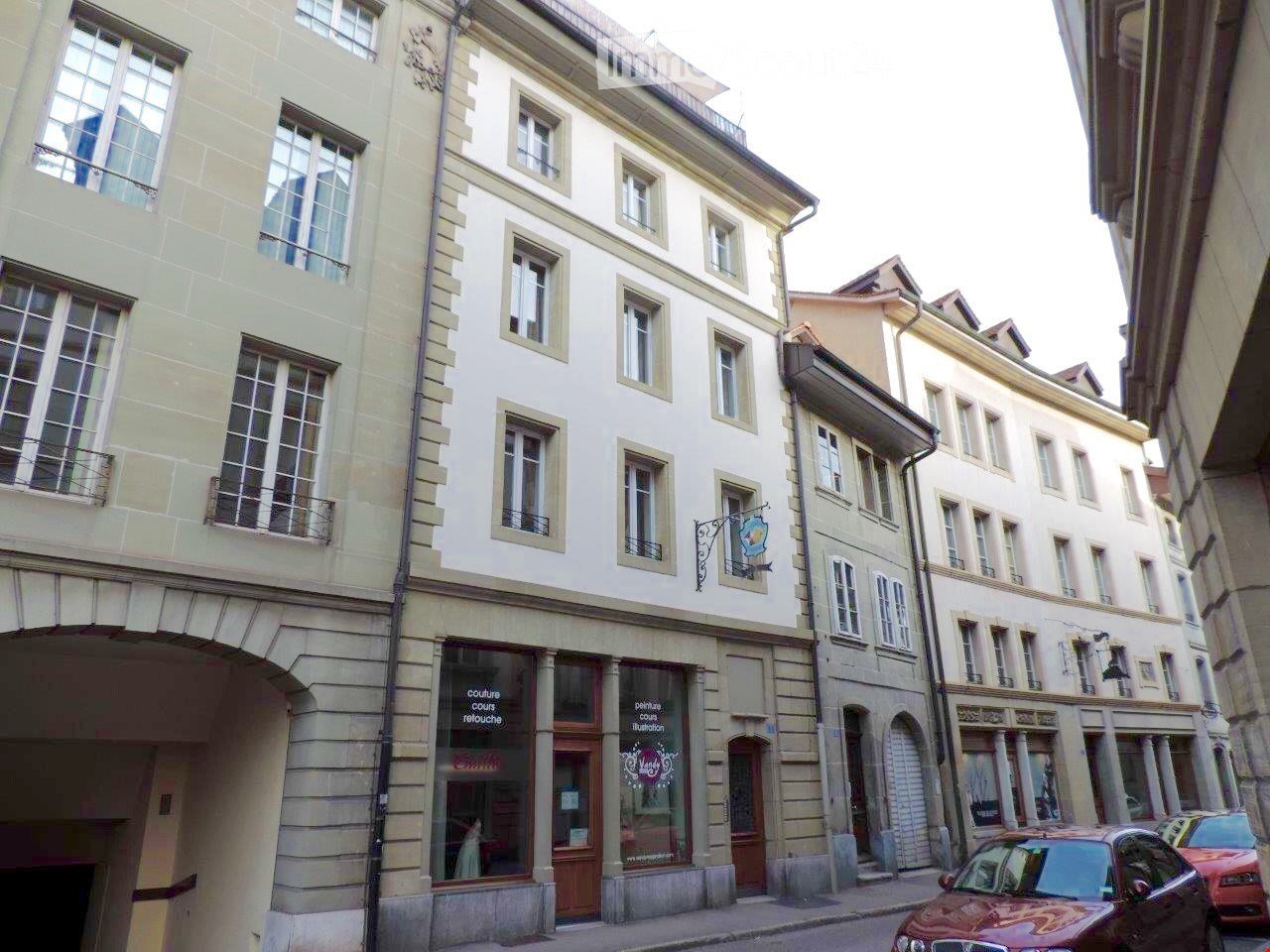 Multi-story building with classic European architecture, large windows, and a storefront at the ground level.