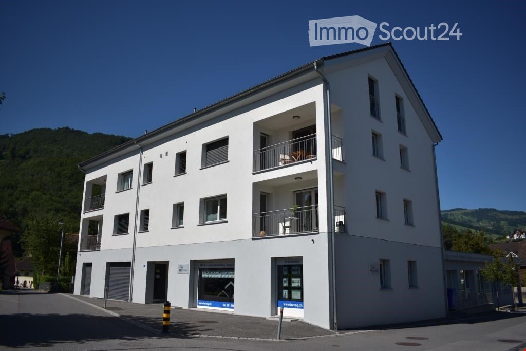 3 story building, white exterior, multiple balconies, garage, windows, door