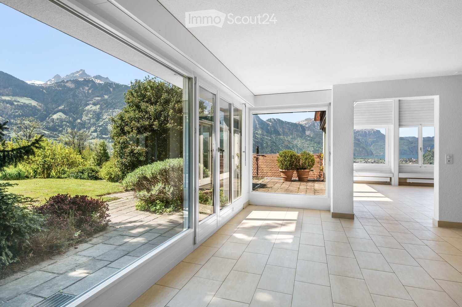 Bright, modern balcony with large glass doors, tiled flooring, and expansive mountain views.