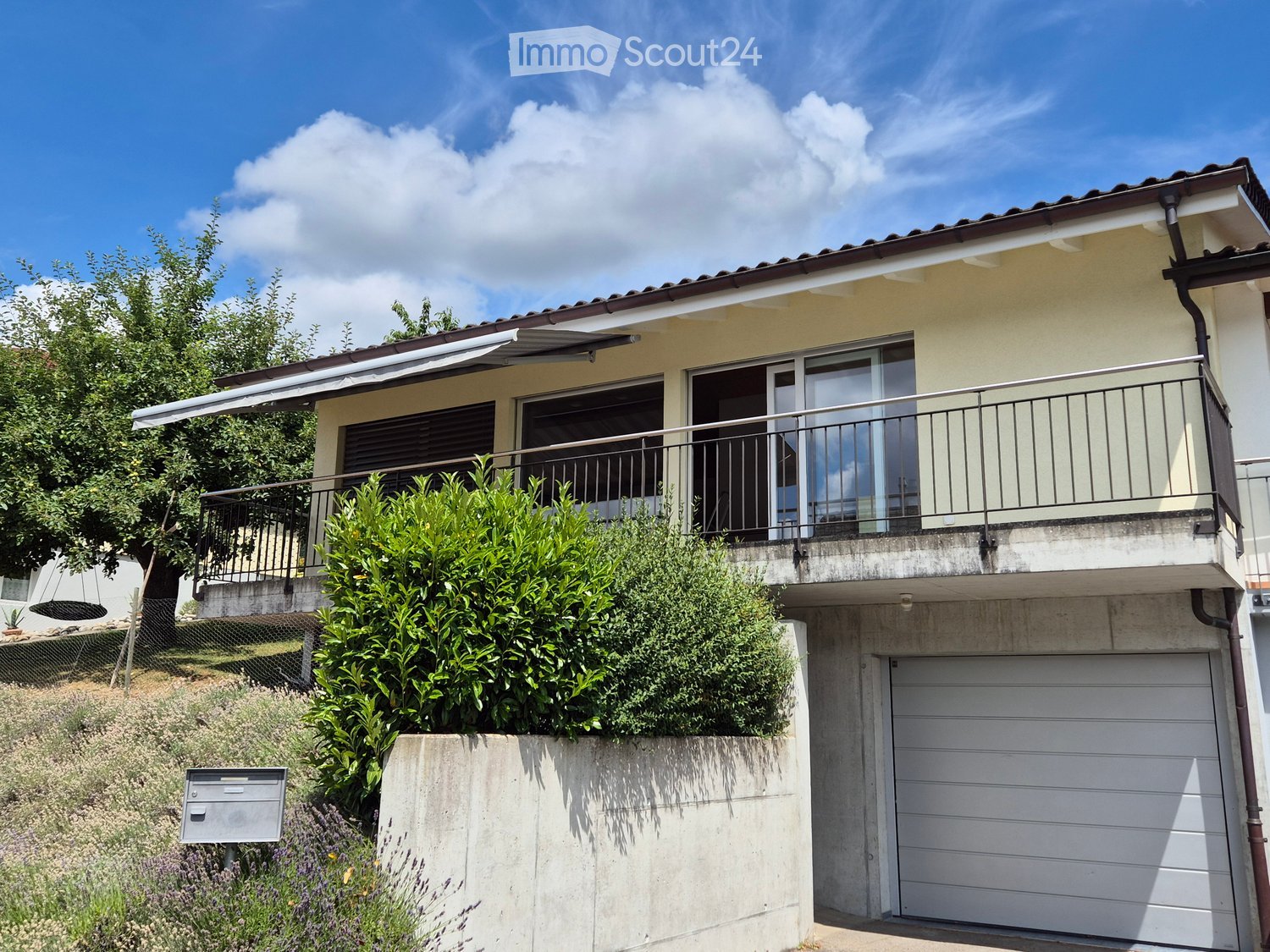 Two-story house with a balcony, garage, and well-maintained garden area.