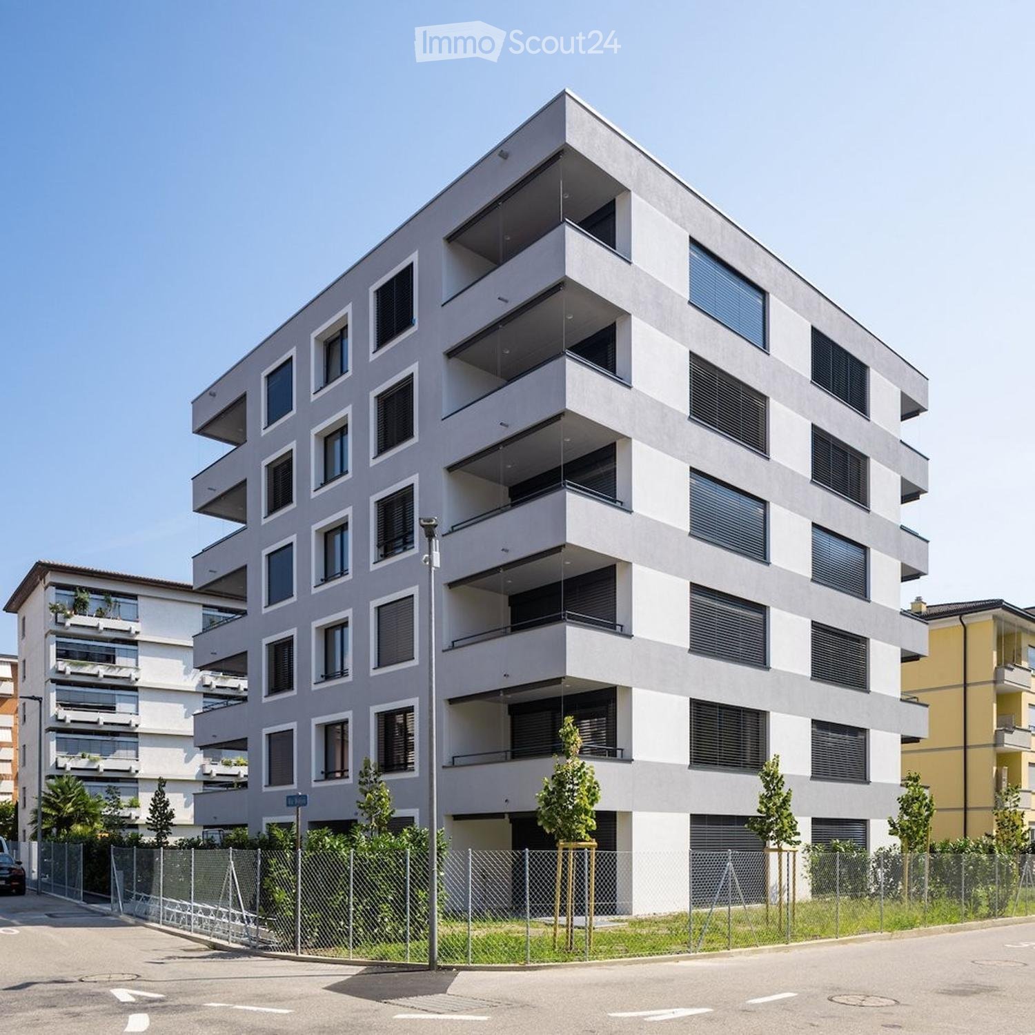 Modern multi-story apartment building with balconies, large windows, and contemporary design.