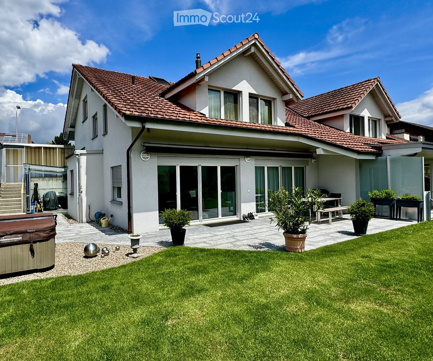 Well-maintained garden with a lawn, patio area, hot tub, and outdoor furniture.