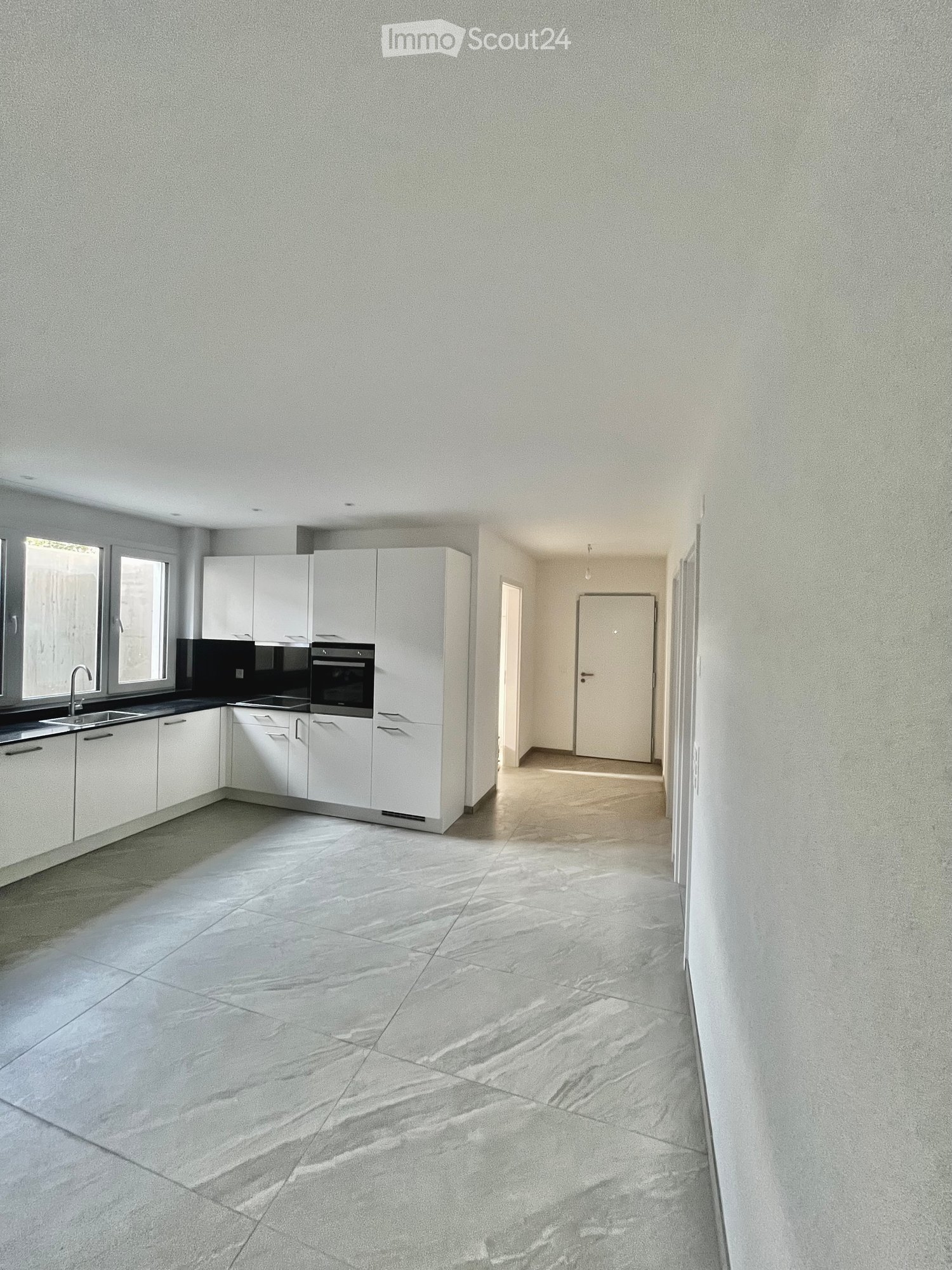modern kitchen with all white cupboards, black countertop, double oven, sink with faucet, large hallway