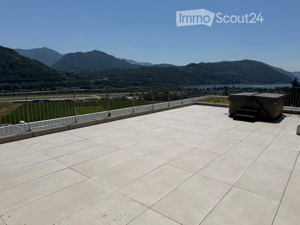 Roof terrace with tiled flooring, metal safety railing, and scenic mountain and lake view.