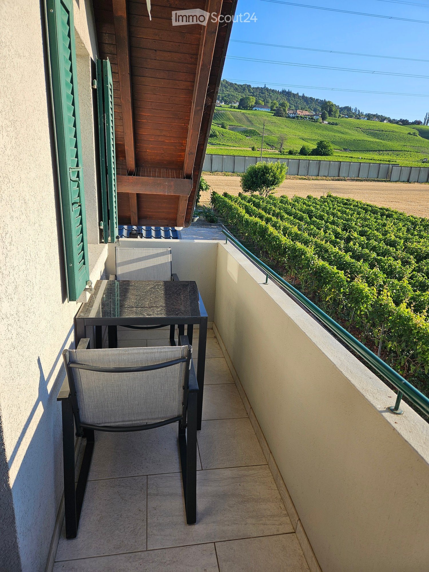 Balcony with a view of vineyards and hills, featuring a table and a chair.
