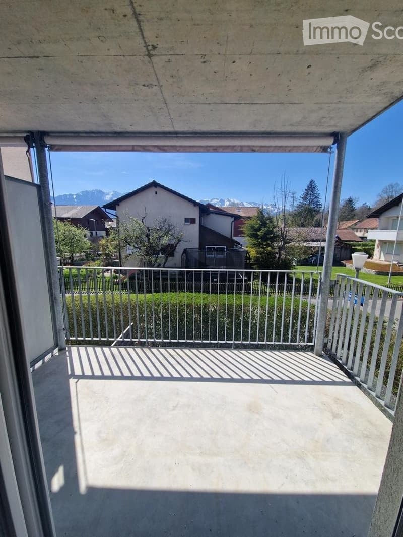 Balcony with metal railing, concrete floor, and scenic mountain view in the background.