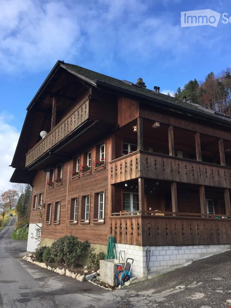 Traditional wooden house with multiple balconies, large windows, and flower boxes.
