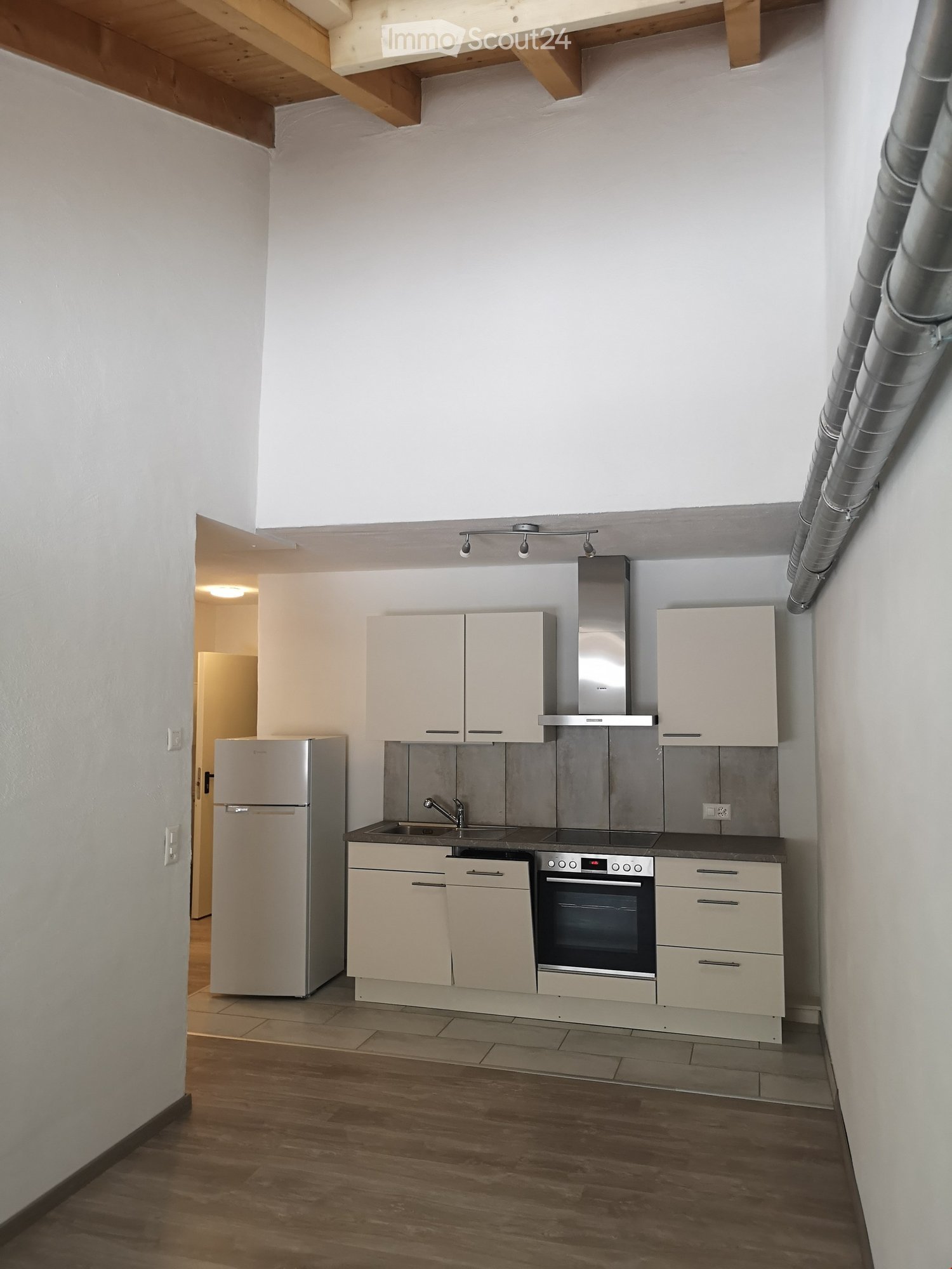 Modern kitchen with light-colored cabinets, stainless steel appliances, and wooden flooring.