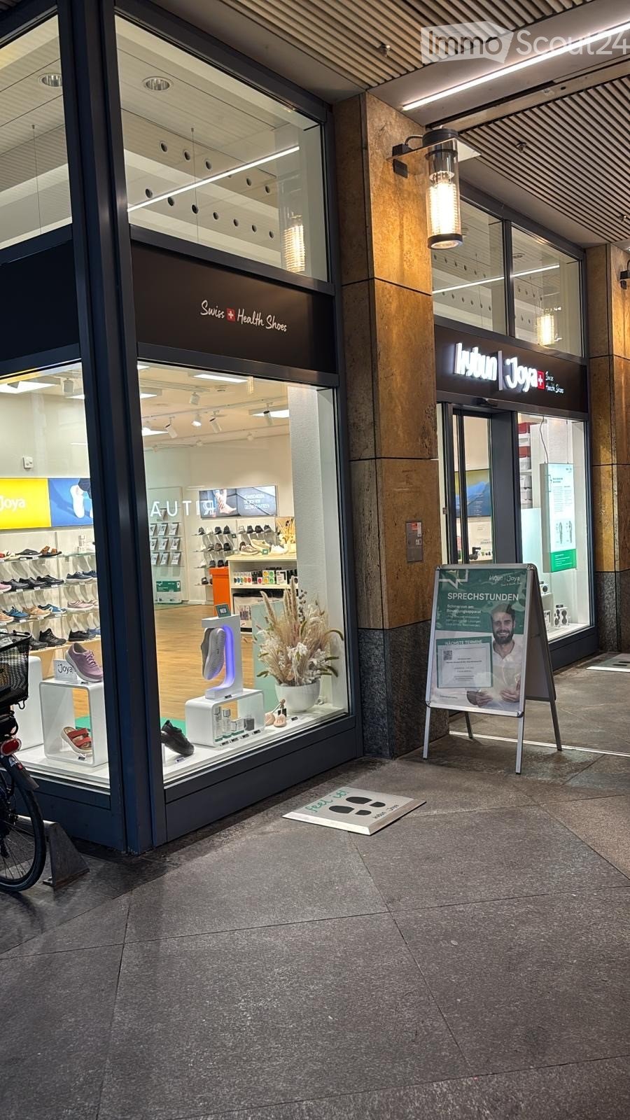 Store with glass door, wooden floor, display of shoes, flower vase, signboard with advertisement, and basket on the bicycle