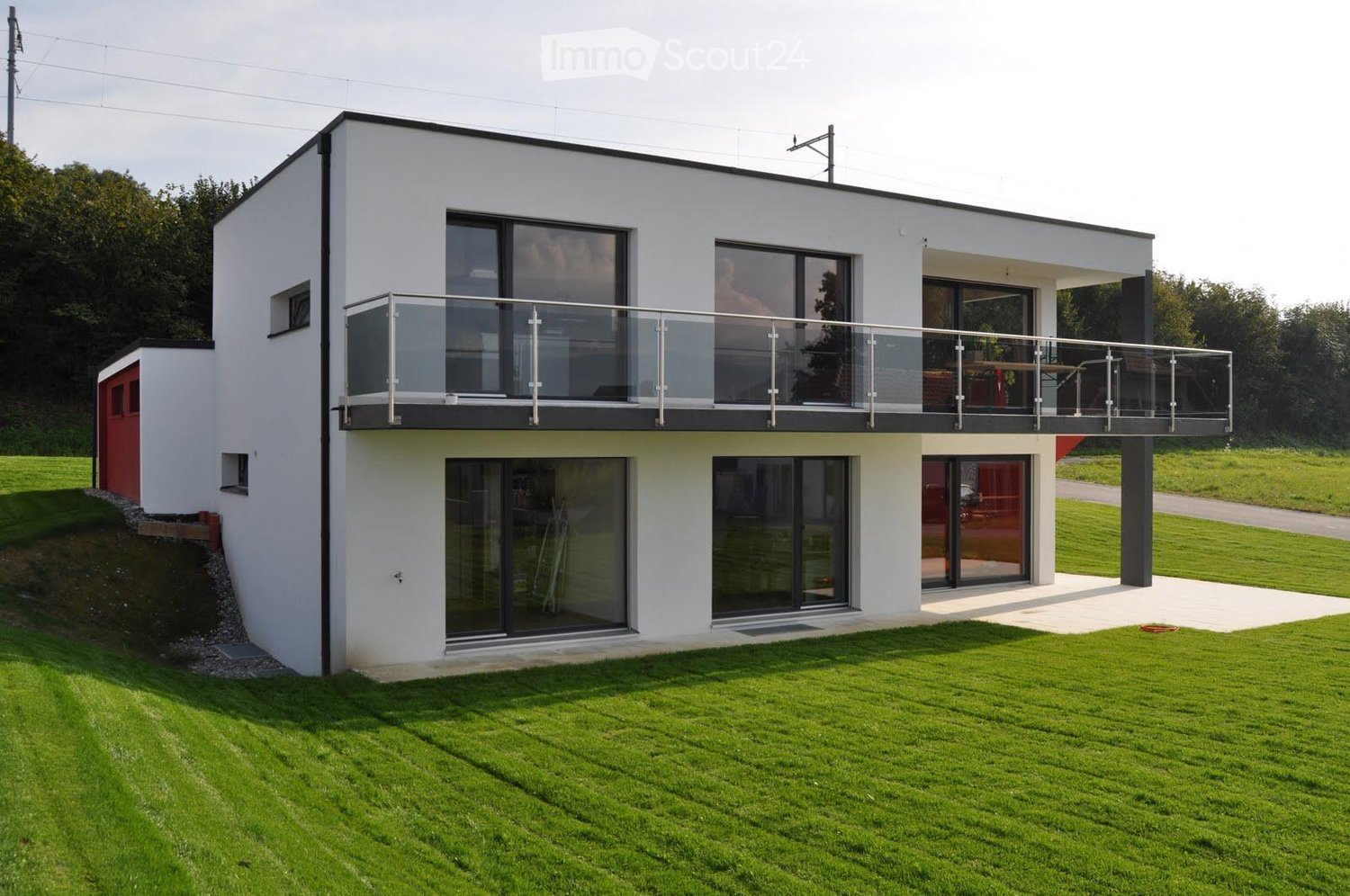 modern white house, glass windows, glass balcony, red door, large green lawn