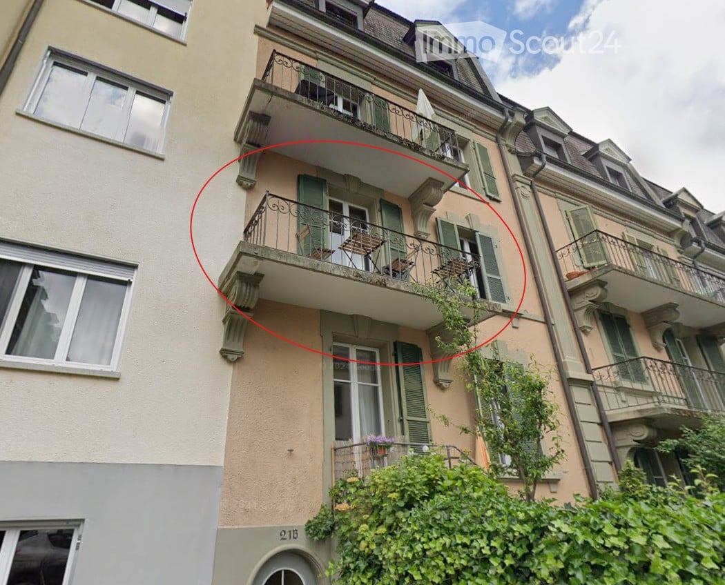 Multi-story residential building with multiple balconies, green shutters, and decorative railings.