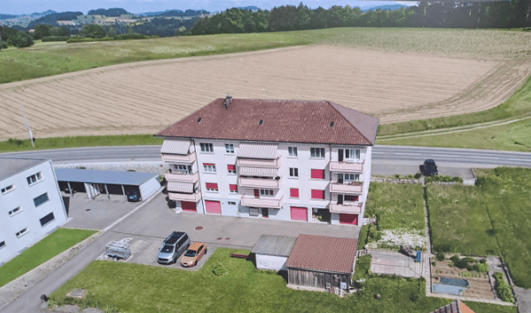 Multi-story residential building with balconies, garage, and parking area.